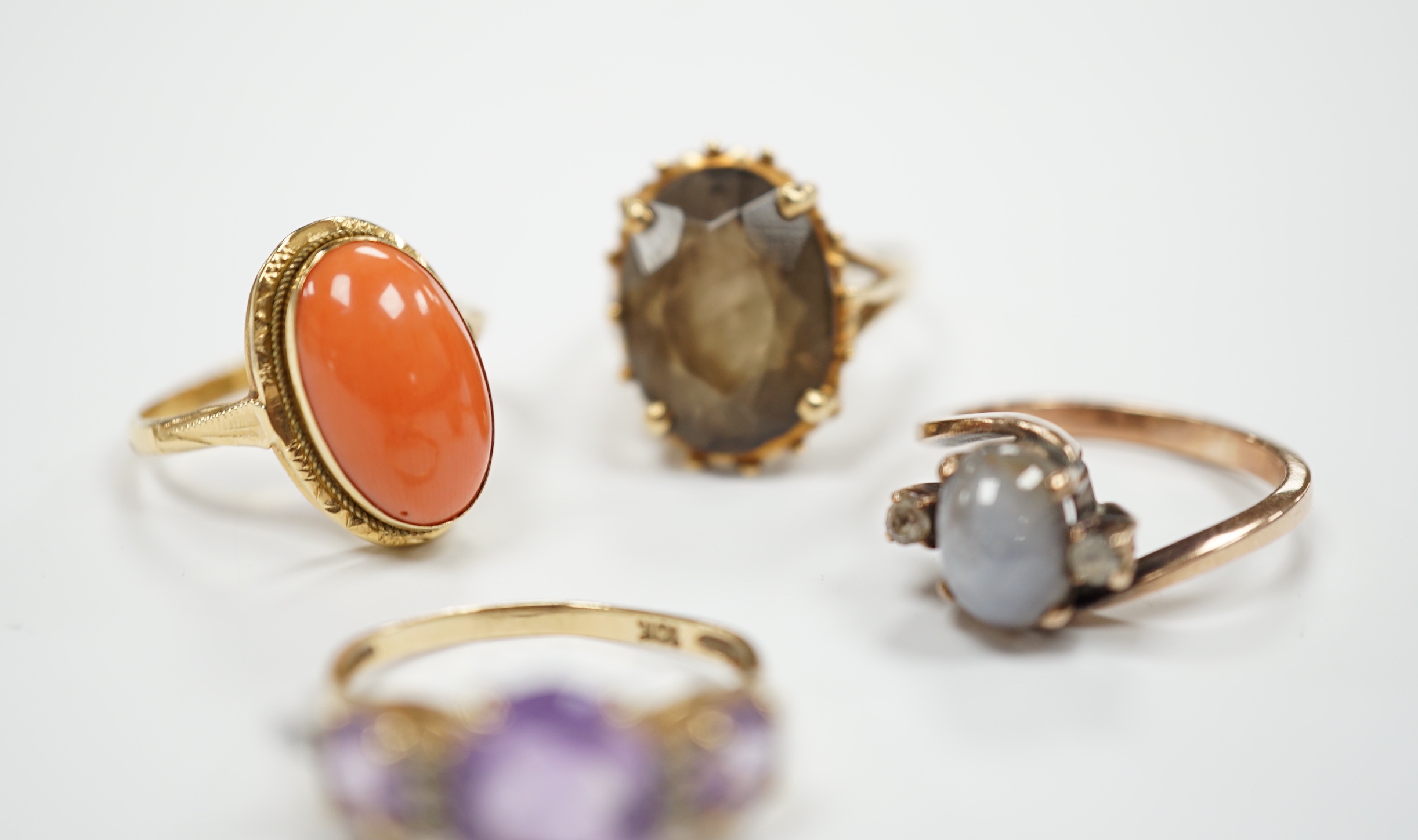 Two modern 10k and gem set rings, including amethyst and diamond chip and two yellow metal and gem set rings including coral set and star quartz? set, gross weight 15.9 grams.